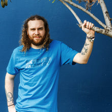 Load image into Gallery viewer, hanging from a tree pensive annoyed model pose look skeeter valentine teal turquoise shirt moist clothing and junk product photo

